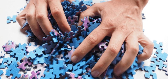 Two hands grabbing blue and purple puzzle pieces