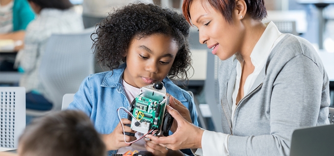 child and adult working on robotics 