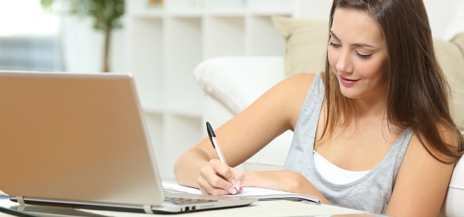 Woman writing at her laptop computer.
