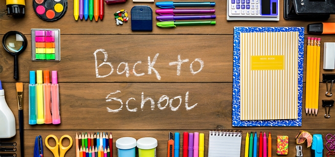 Writing in chalk stating "Back To School"" surrounded by typical school supplies.