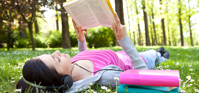 A girl lies on the grass, reading a book