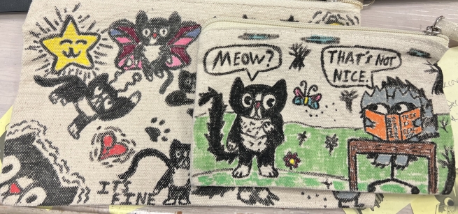 Image of two pouches that have drawings of cats. 