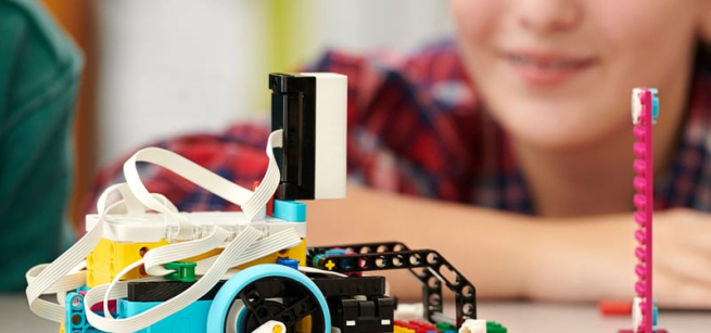 Image of LEGO robot in foreground with a blurred image of a youth maker in the background.