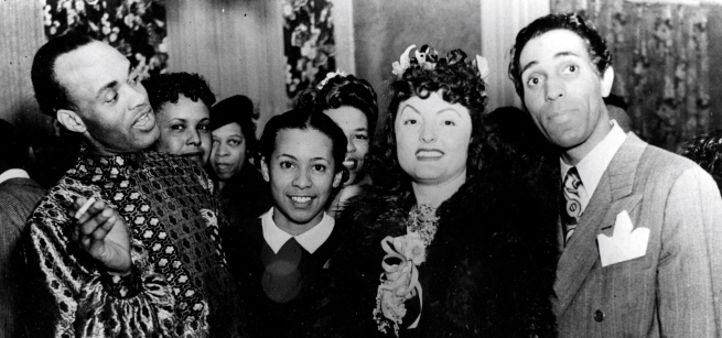 men and women in evening clothes standing together and smiling at the camera