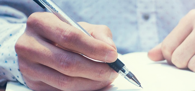 Hands writing in a notebook.