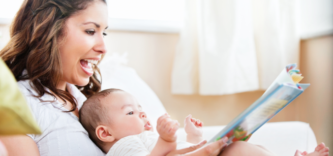 A woman holds a baby and a book