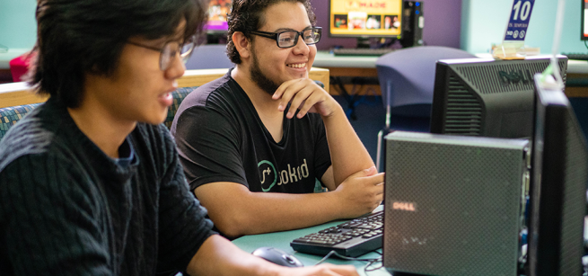 Teens smiling while using computers. 