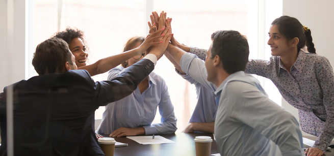 office workers high fiving over a desk