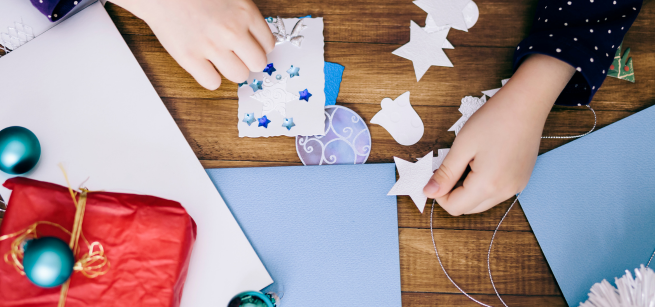 hands are making a snowflake card with cardmaking supplies around them