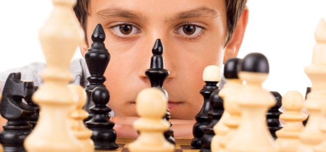 A young chess player is looking at the chess board
