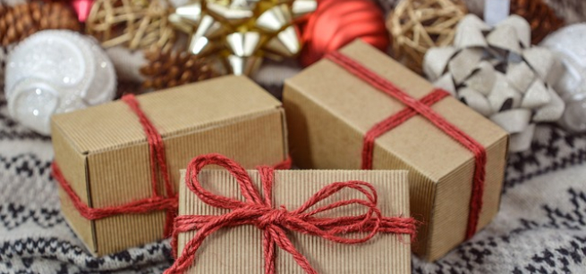 Brown packages tied with red string, with holiday decorations in the background, Image by Monika from Pixabay