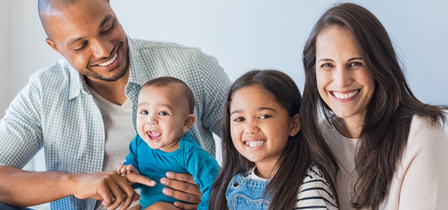 smiling family of four with parents, girl and baby boy