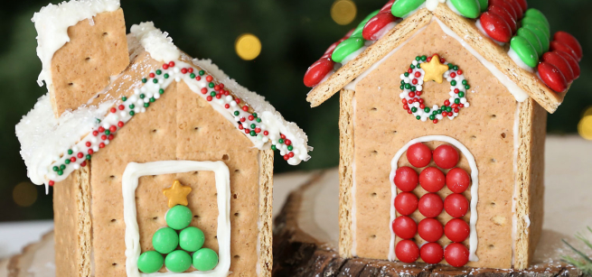 Two gingerbread houses made of graham crackers, white frosting, and various colorful candies are on display. 