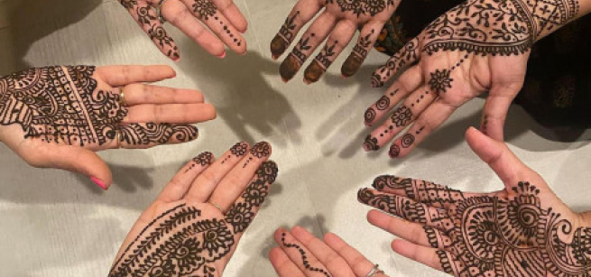 Seven hands featuring henna paste on the palms.