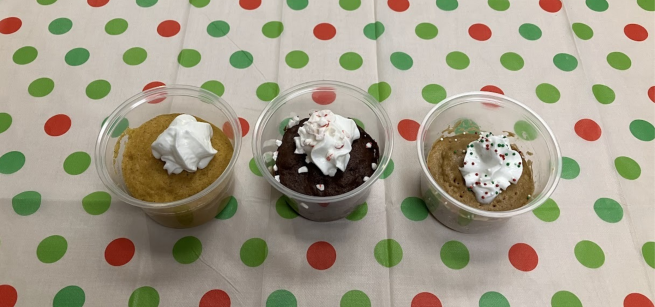 Three decorated mug cakes on a red and green polka-dotted tablecloth