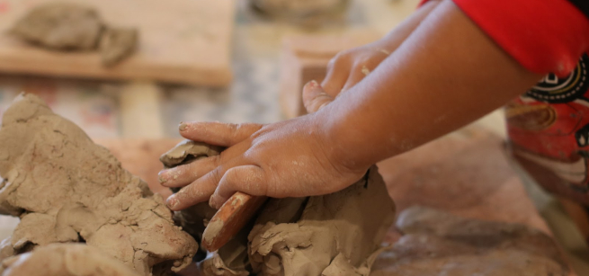 A child's hands explore a mound of clay.