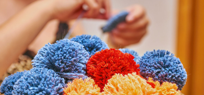 Bunches of homemade pom poms with maker in background
