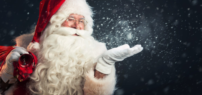 Santa stands in front of a blue background with a magic light in his hand