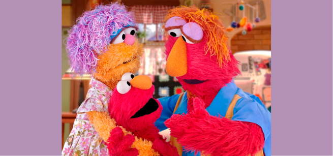 Sesame Street characters are in the photo with Elmo's parents giving him a hug and explaining something important to him. 