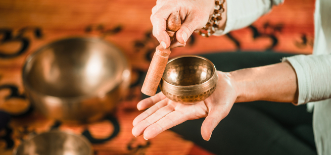 A person striking a sound bowl.