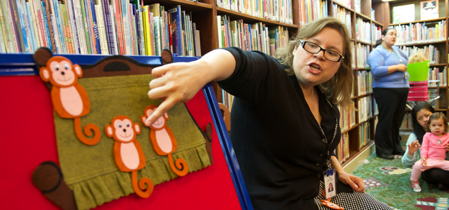 librarian points to a felt monkey on a flannel board story
