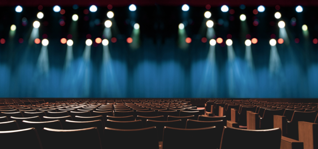 Darkened theater stage viewed from behind seating.
