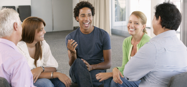 Group of adults sitting in chairs in a circle having a lively conversation