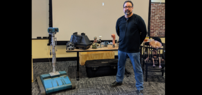 Man standing next to a table of robotic devices