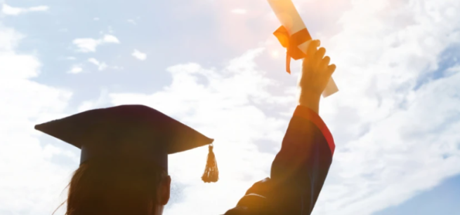 Shadow of a person holding up a diploma and wearing a cap and gown