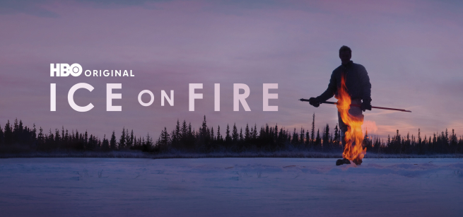 A person holding a stick with a fire in front of him. 