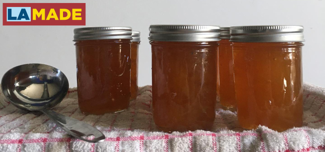 4 glass jars filled with jam and a ladle