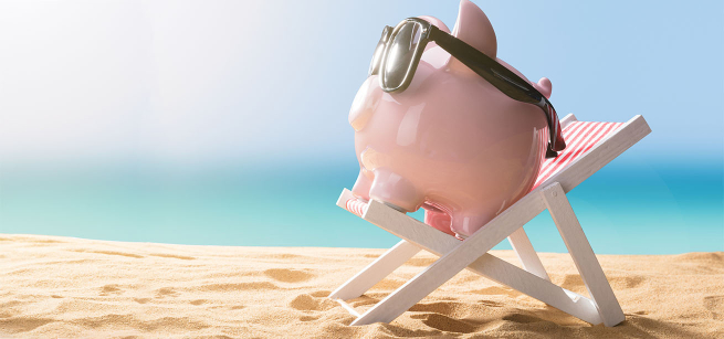A relaxing, pink piggy bank wearing sunglasses sitting on a beach chair at the beach