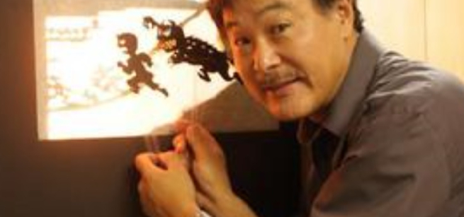 Man holding up shadow puppets on a screen