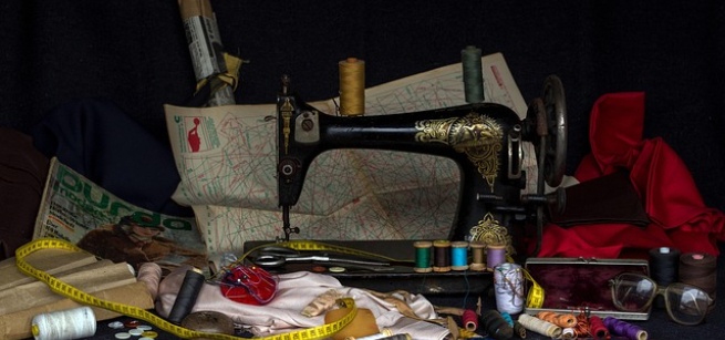A color photo of a vintage sewing machine, surrounded by sewing paraphernalia, Image by andreas N from Pixabay