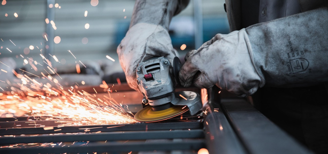 worker with a tool working on an iron beam sparking some fire 