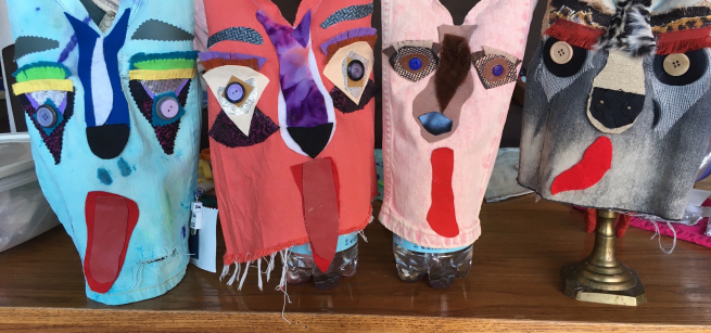 Four colorful dog puppets lined up in a row. 