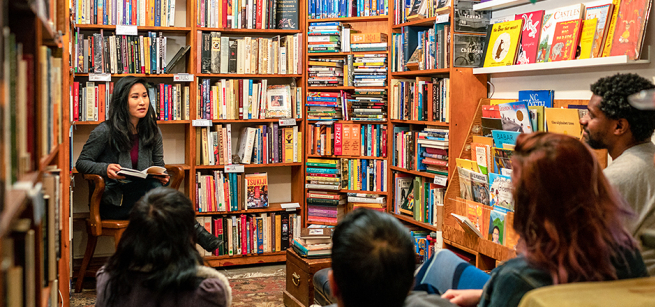 book shelves with books and adult sitting in a group