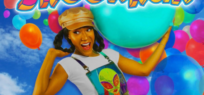 Cheri Jacobs of Snooknuk and Friends wearing a white t-shirt and colorful alien print overalls with a multi-colored balloon backdrop. 