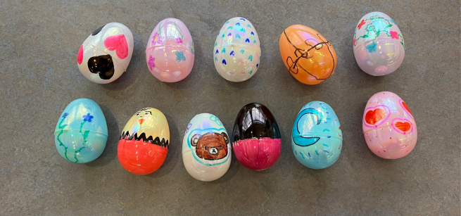 Eleven plastic eggs decorated with marker drawings