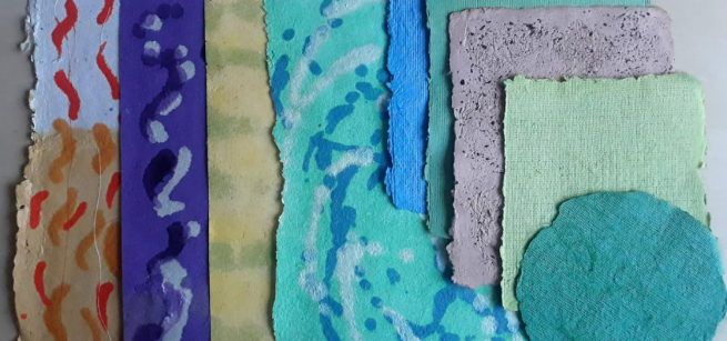An assortment of handmade paper in different colors, shapes, and styles laid out on a flat surface.