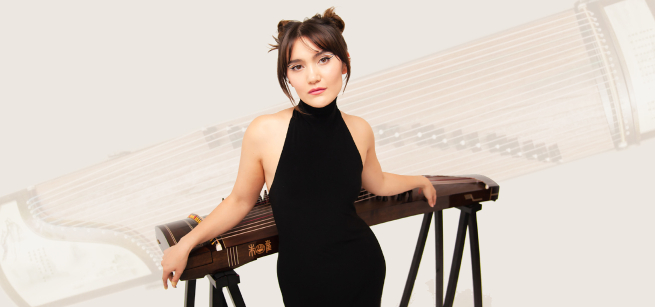 A women named Jett Kwong is dressed in black and leaning on a musical instrument called a Guzheng. 