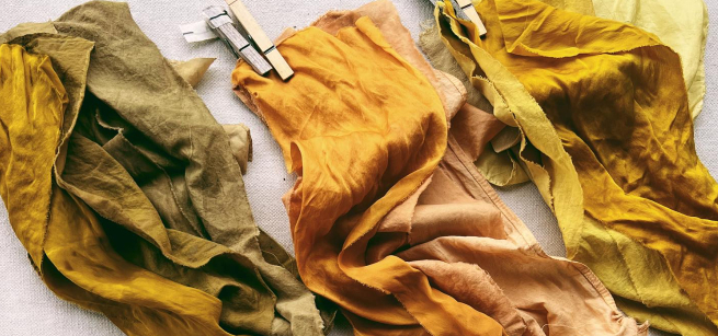 Three pieces of cloth laying next to each other in shades of green and yellow, held by clothespins