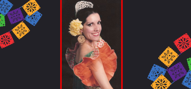 A woman in a dance costume surrounded by papel picado. 