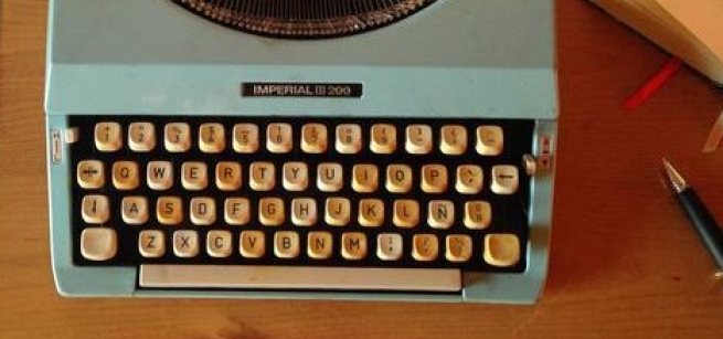 Typewriter and pen sit on a desk