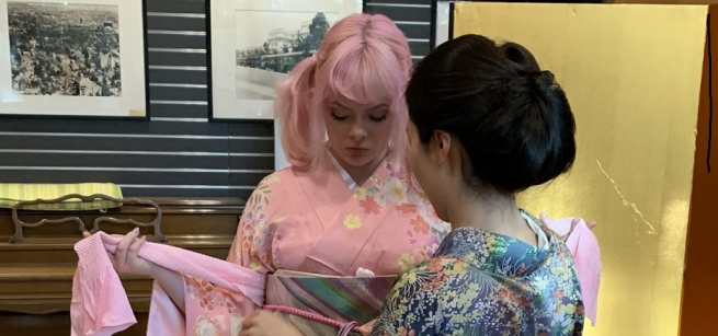 Two women in kimono tying obi