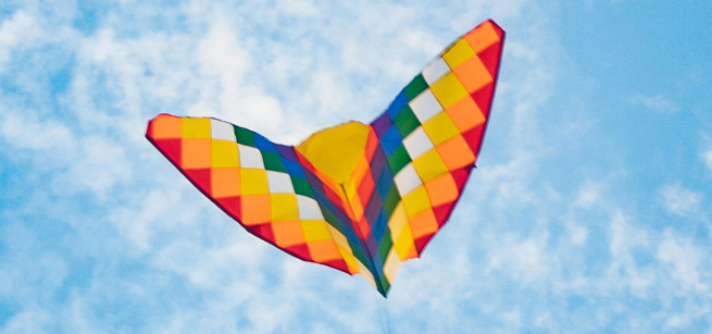 Butterfly shaped kite flying against a blue sky