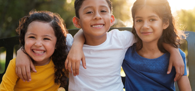 three children smiling with arms around each other