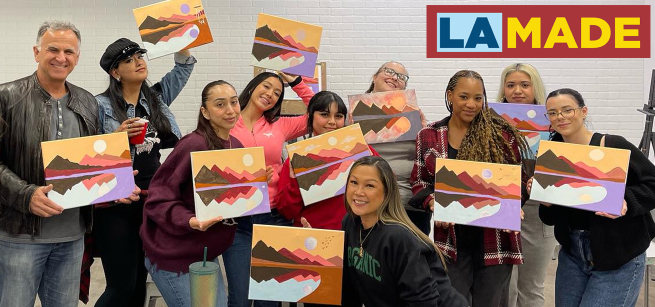 adults smiling while holding up their paintings