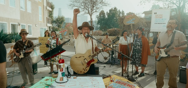 Zosimo Quibilan holding a guitar with his fist in the air.