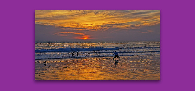 Three kids playing in the surf at sunset.